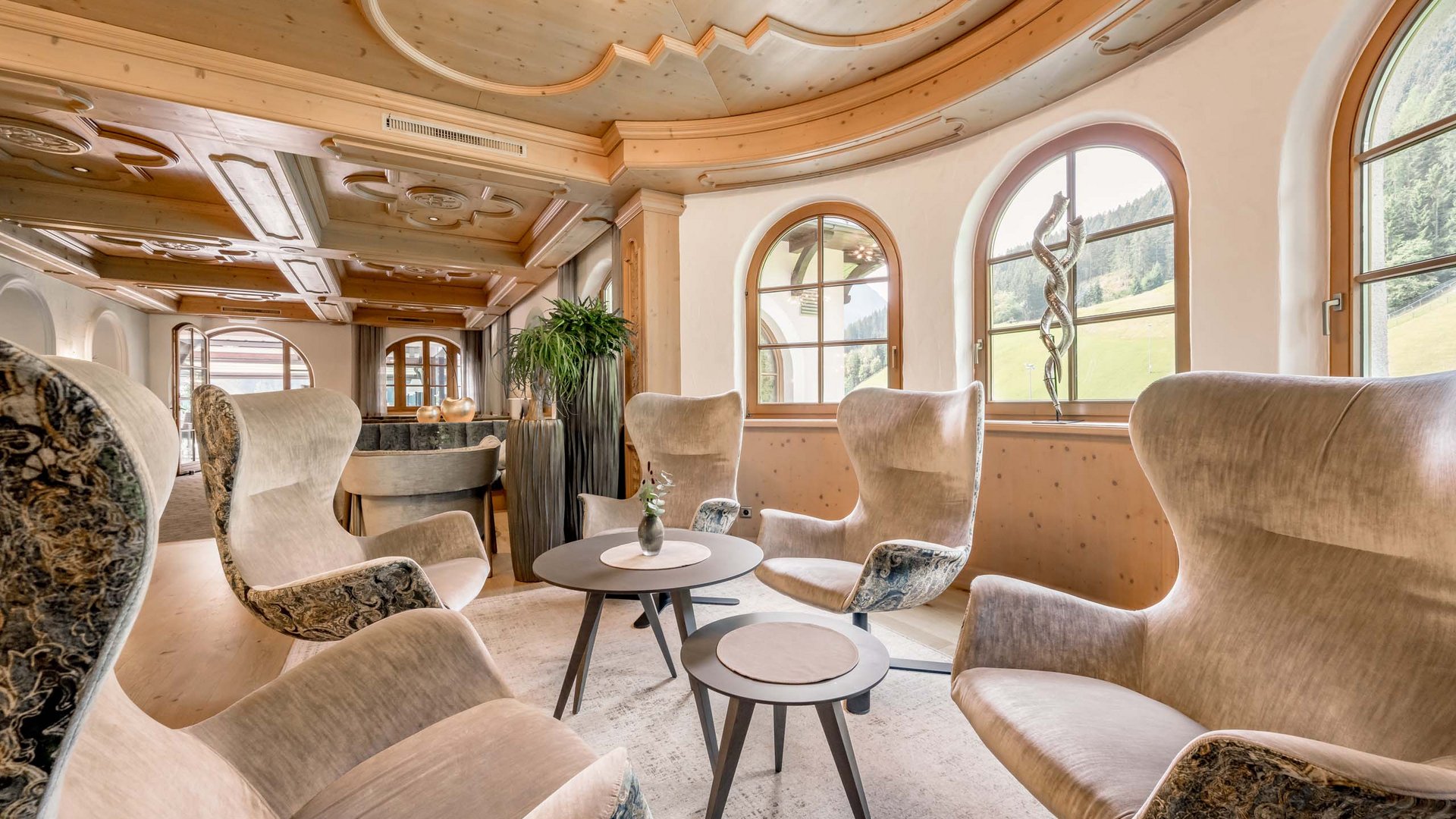 Stubaital: das Hotel mit Pool Gemütliche Lounge mit gepolsterten Sesseln und großen Fenstern in Holzstil