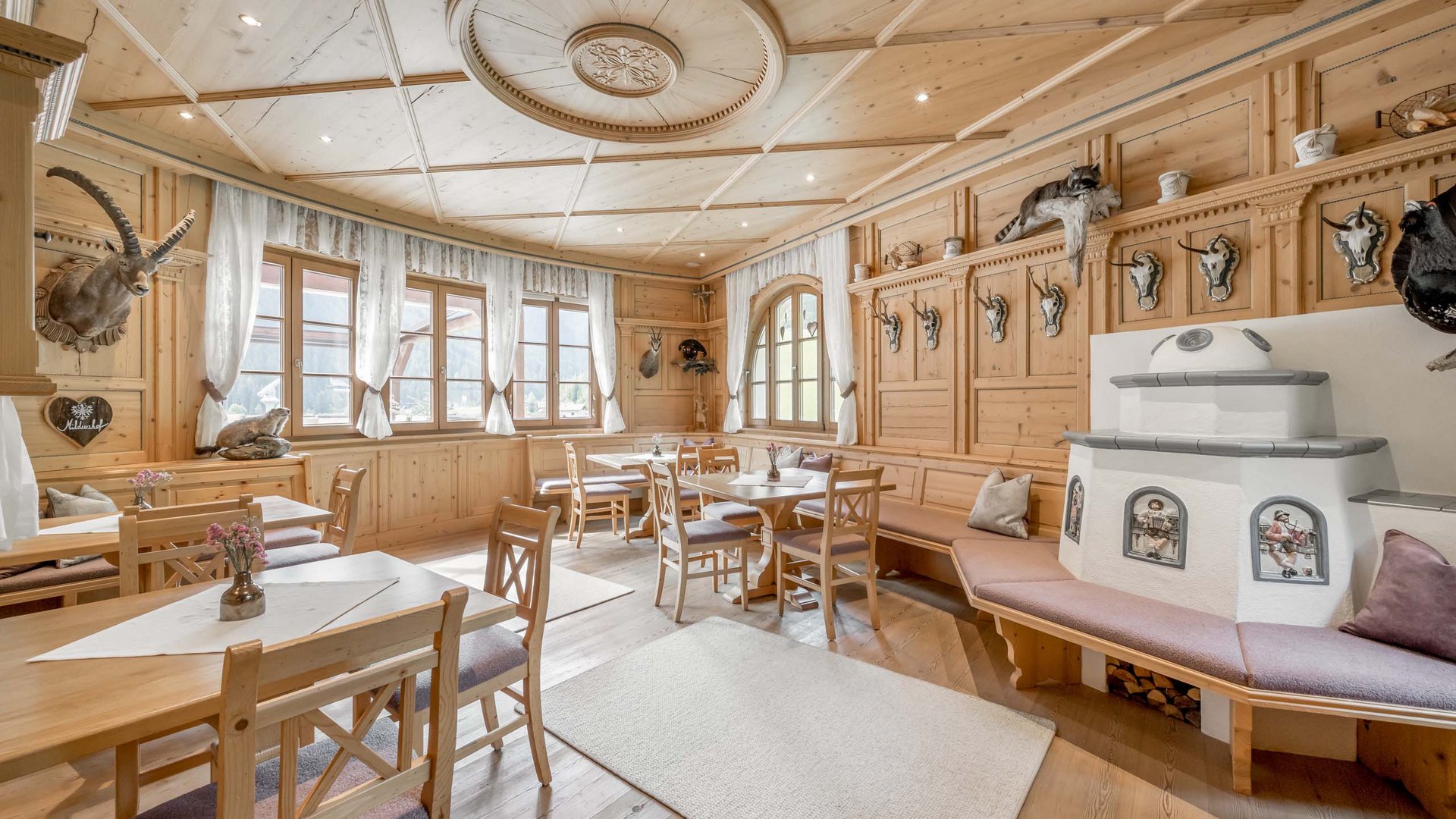 Stubaital: das Hotel mit Pool Gemütlicher Gastraum mit Holzmöbeln und traditionellen Jagdtrophäen an der Wand