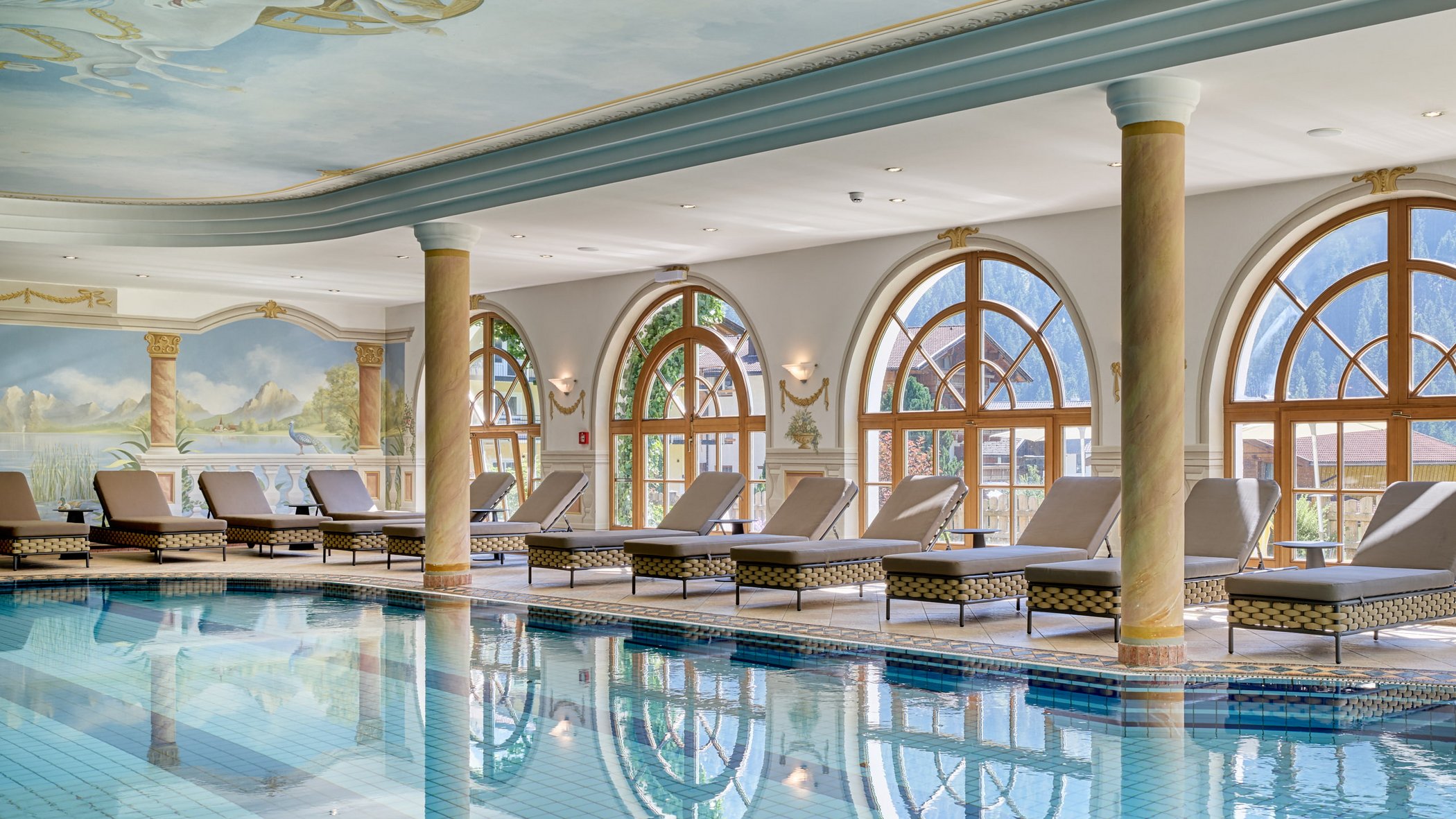 Stubaital: das Hotel mit Pool Eleganter Innenpool mit Liegestühlen und großen Fenstern mit Bergblick