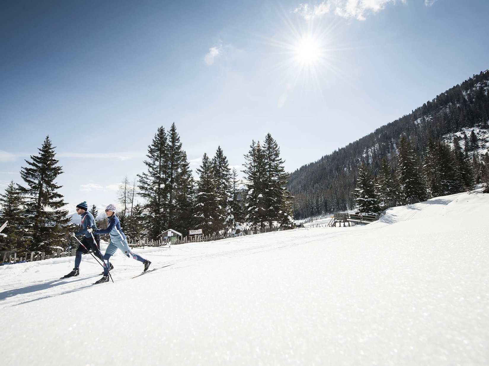 Stubaital: das Hotel mit Pool Zwei Skilangläufer bei sonnigem Wetter in verschneiter Berglandschaft