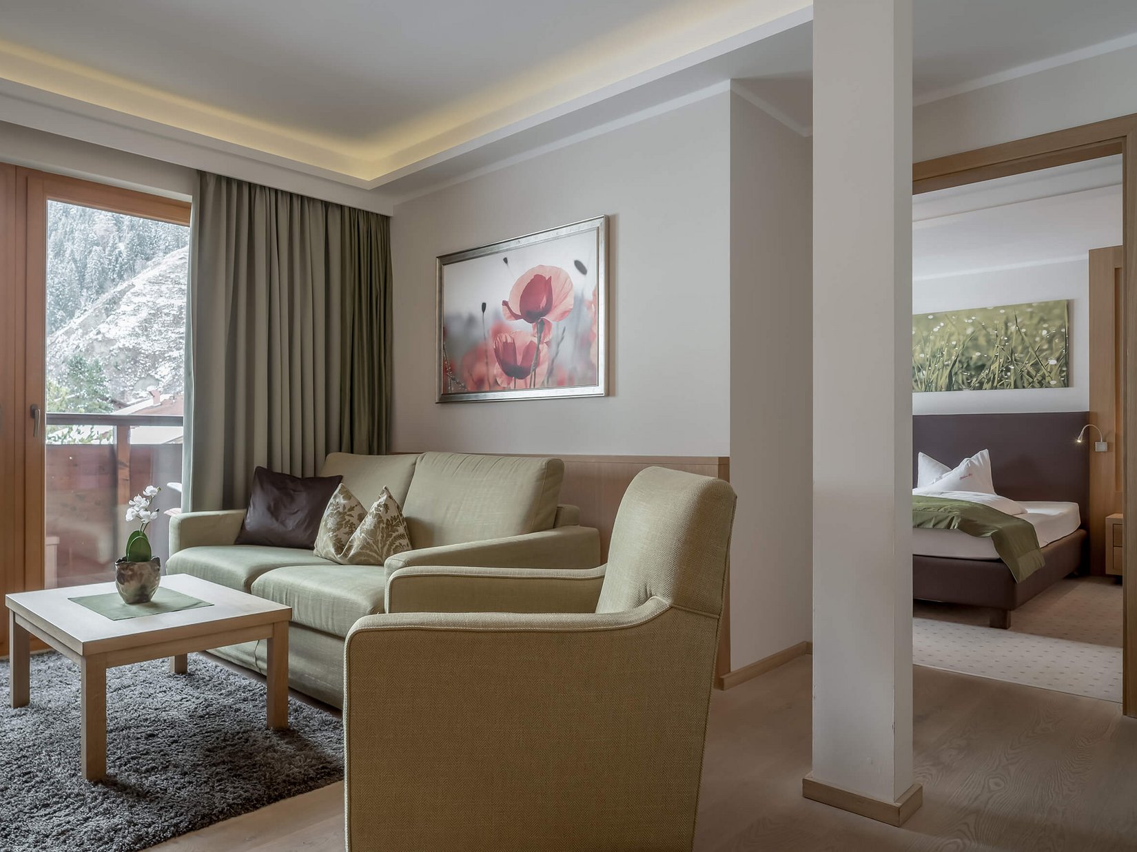 Stubaital: das Hotel mit Pool Gemütliches Wohnzimmer mit Sofa, Sessel und Blick auf Schlafzimmer und Balkon