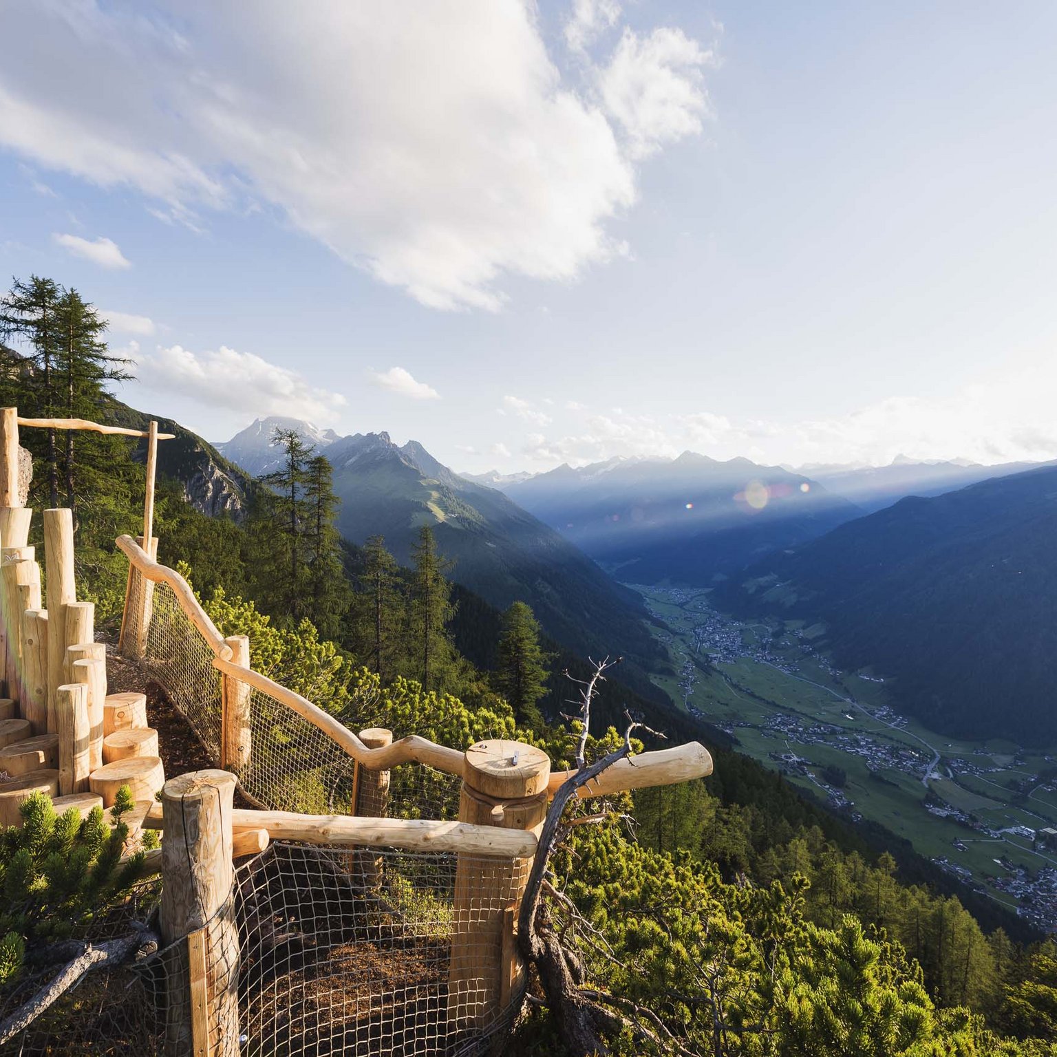 Stubaital: das Hotel mit Pool Holzaussichtspunkt mit Blick auf Tal und Berge bei Sonnenuntergang