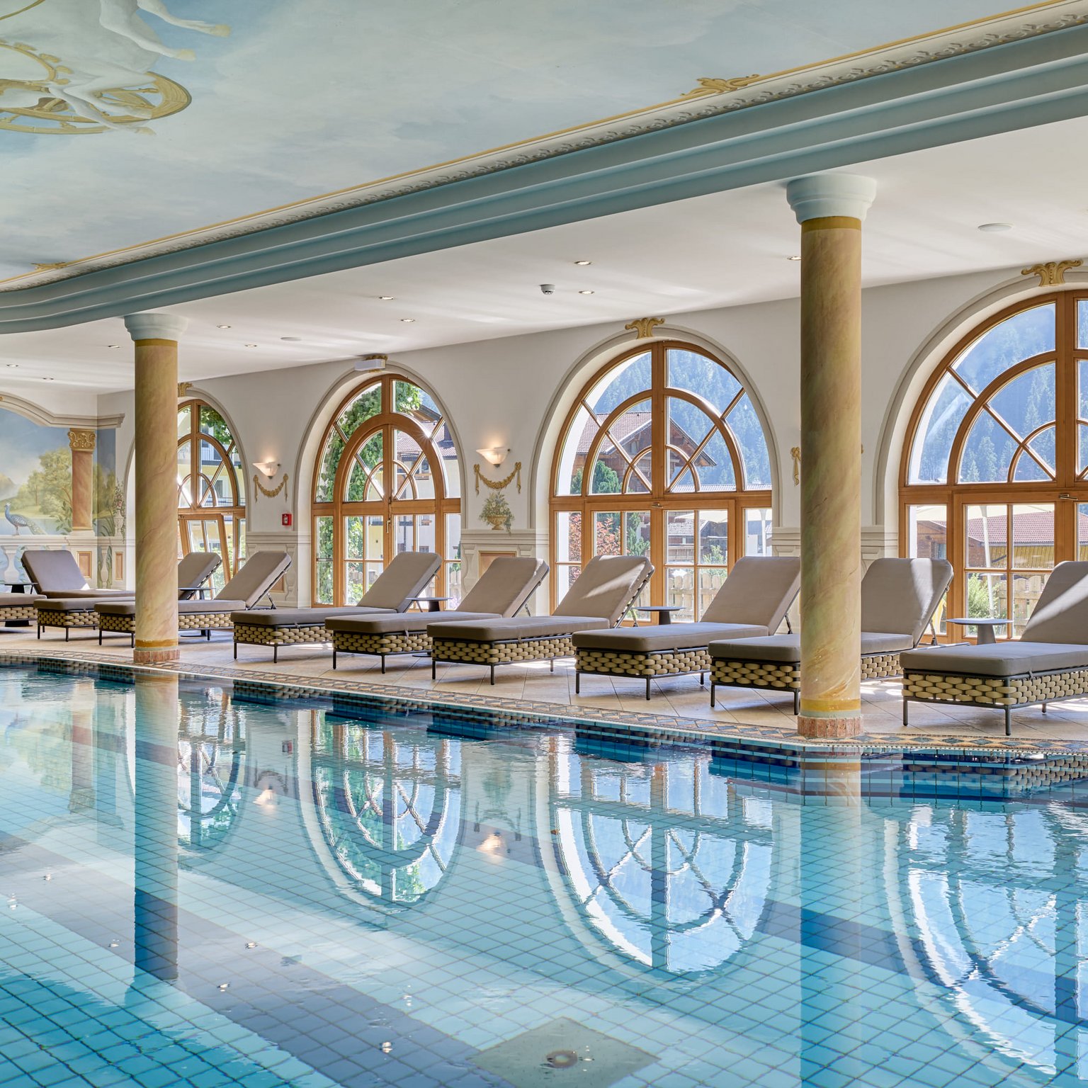 Stubaital: das Hotel mit Pool Eleganter Innenpool mit Liegestühlen und großen Bogenfenstern mit Bergblick