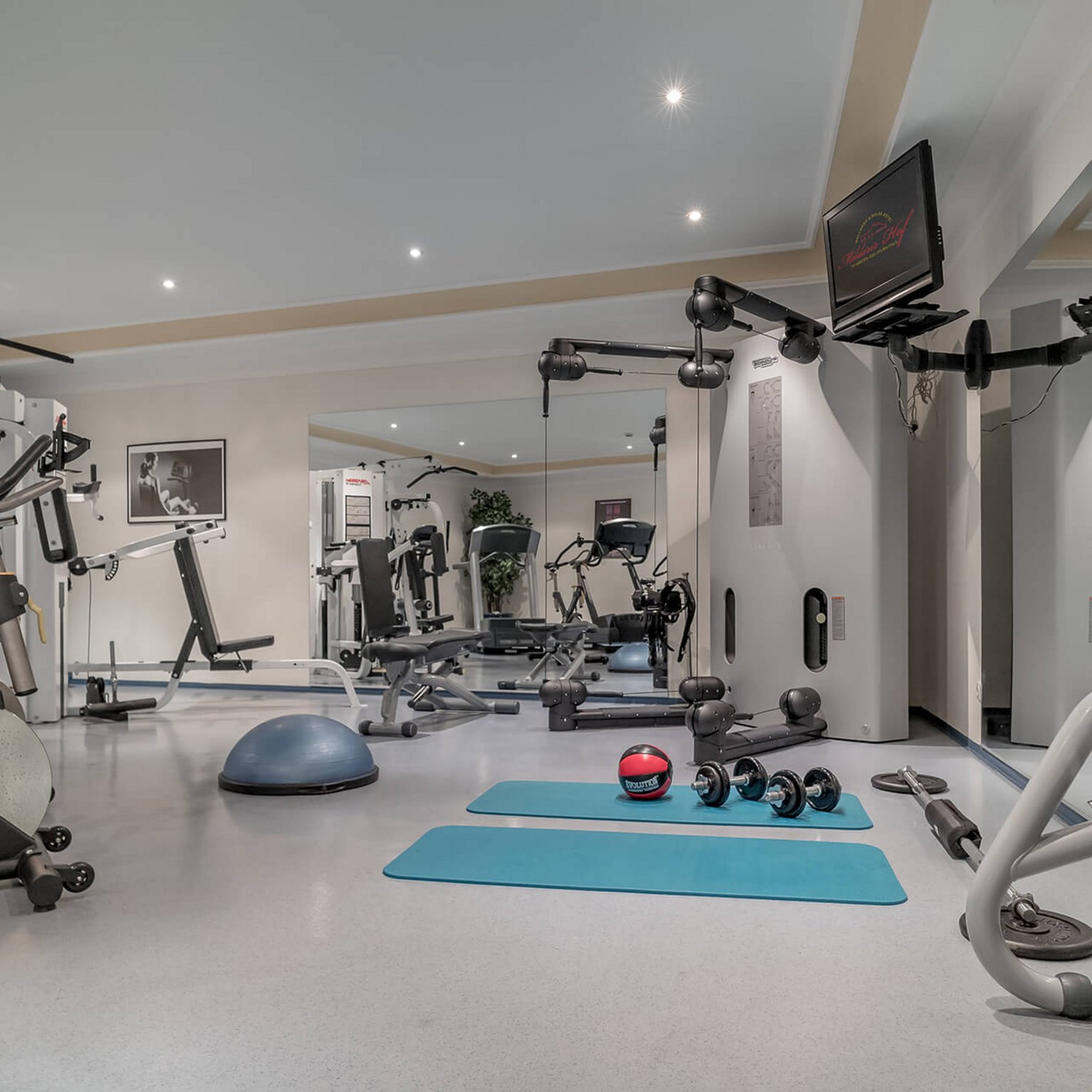 A 4-star hotel in Tyrol: wellness & fitness Modern gym with equipment, dumbbells, mats, and mirrored wall