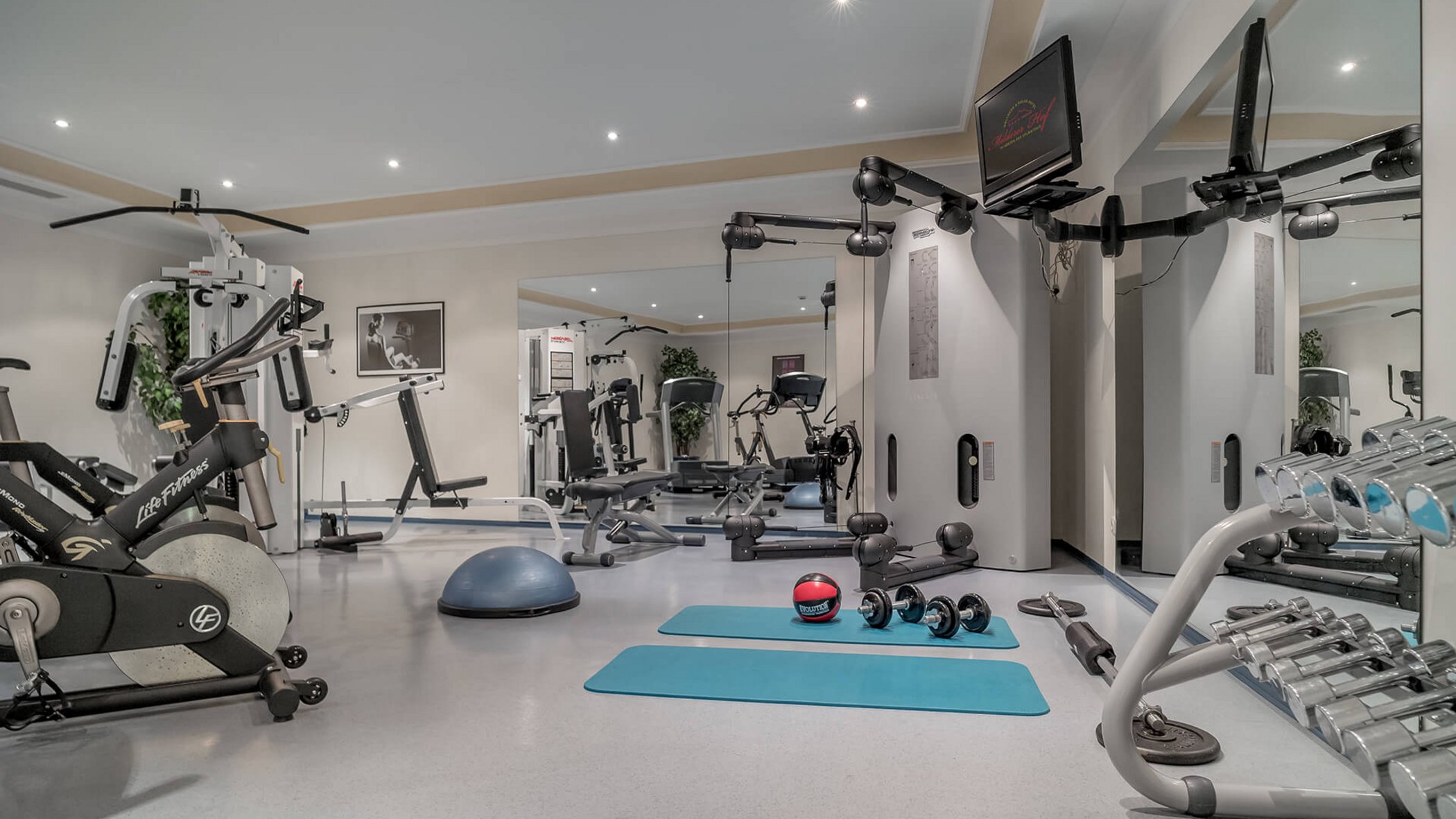 A 4-star hotel in Tyrol: wellness & fitness Modern gym with equipment, dumbbells, mats, and mirrored wall