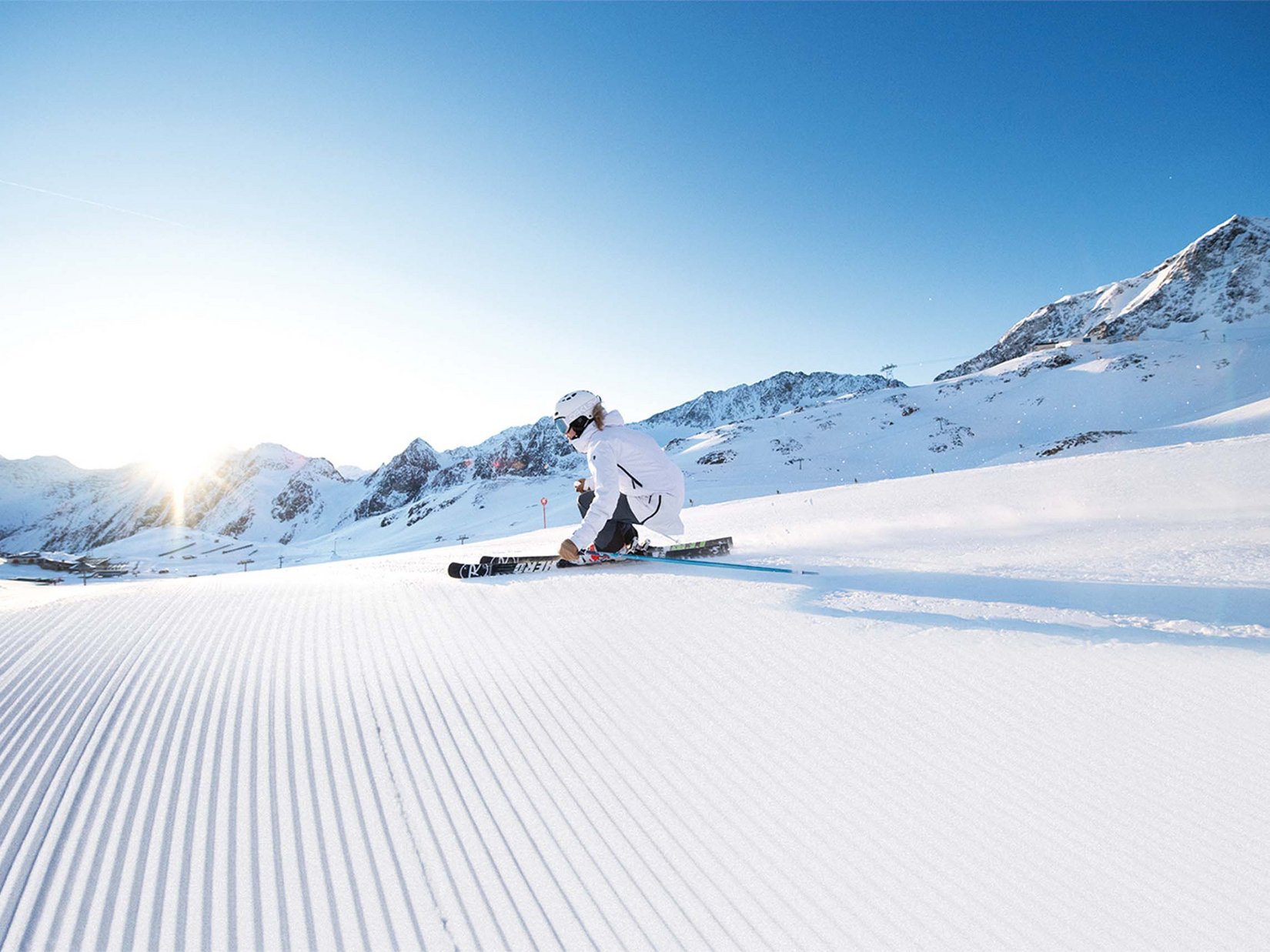 Stubaital: das Hotel mit Pool Skifahrer in weißer Kleidung fährt an sonnigem Tag auf frischem Schnee