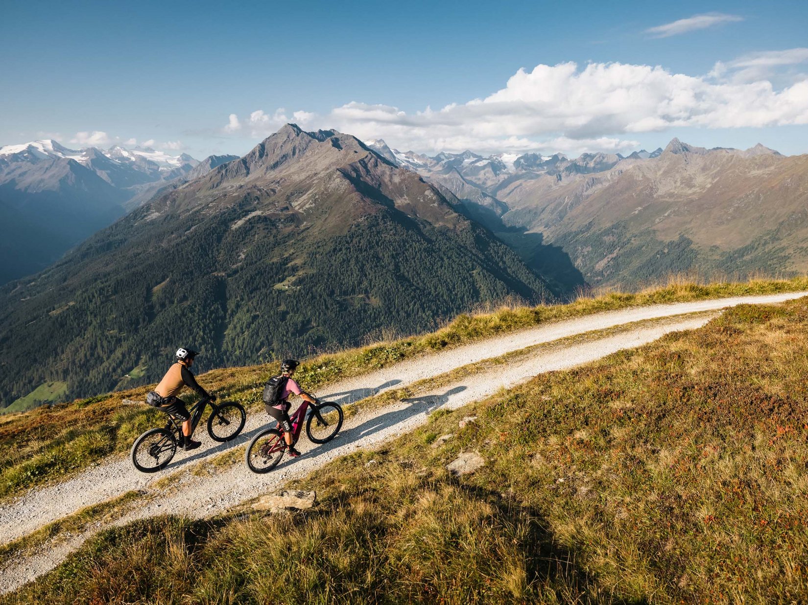 Stubaital: das Hotel mit Pool Zwei Mountainbiker fahren auf einem Bergweg mit Alpenpanorama