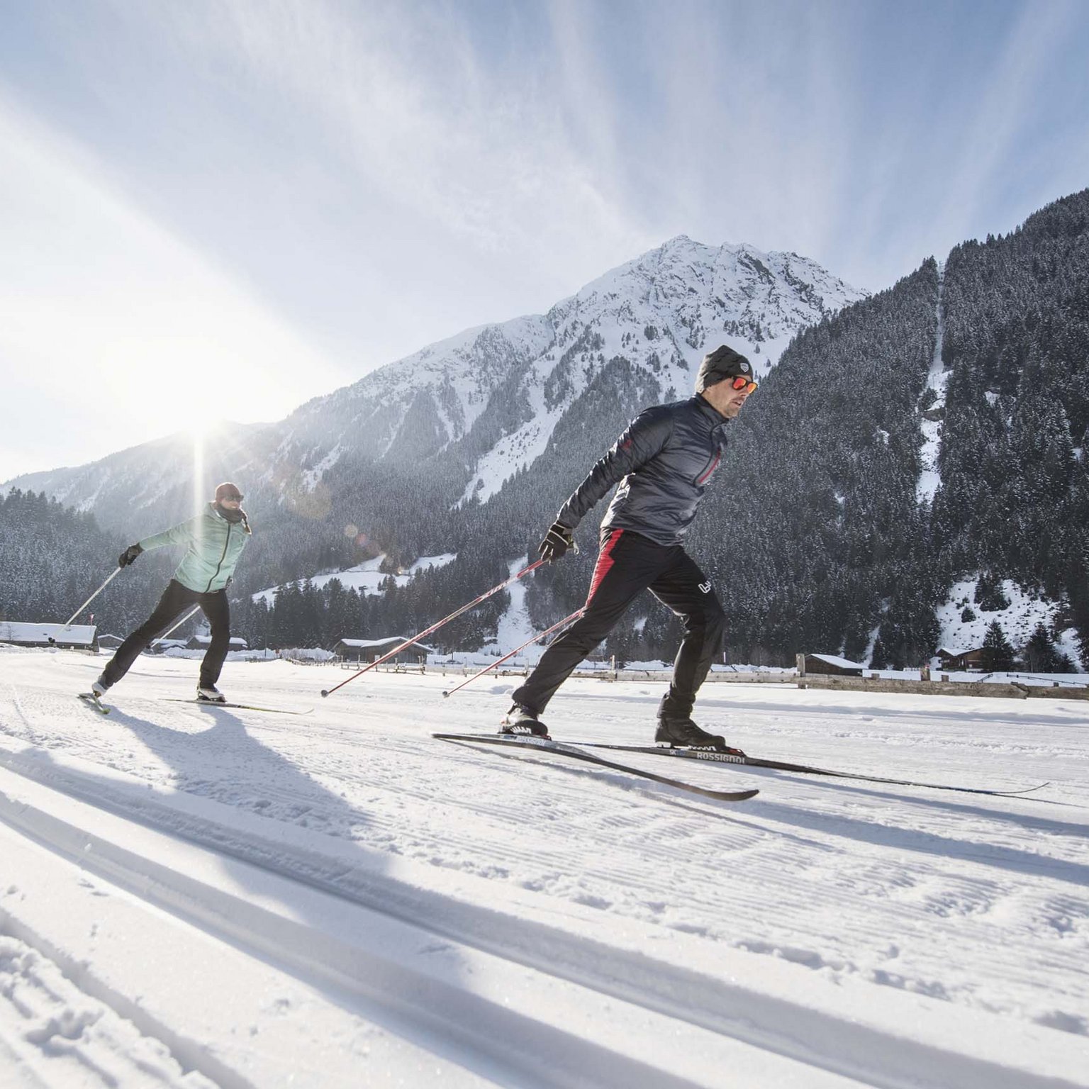 Stubaital: das Hotel mit Pool Zwei Personen Langlaufen bei sonnigem Winterwetter in den Bergen