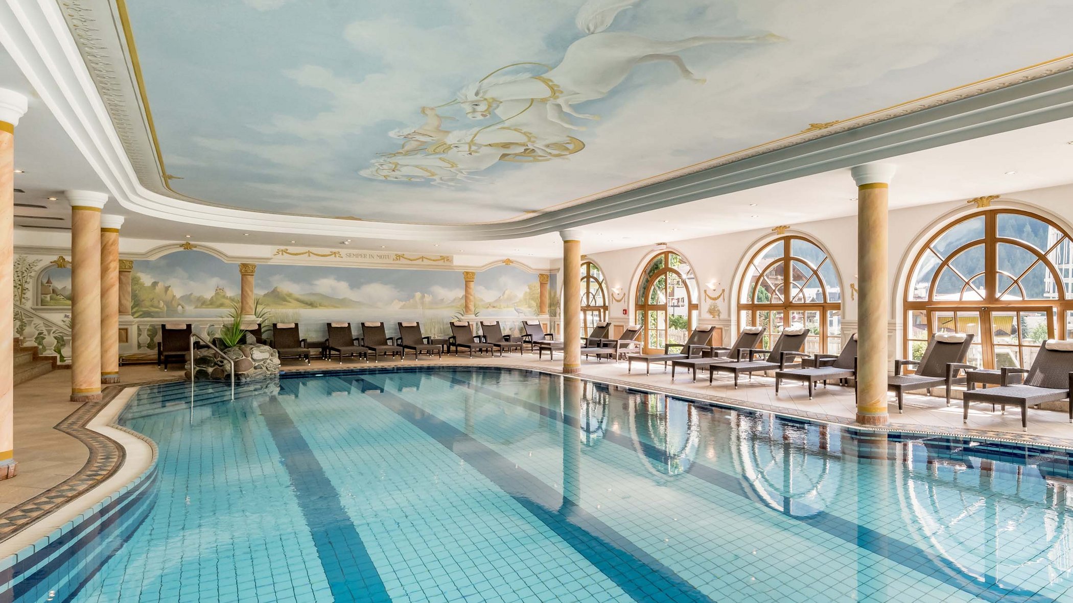 Stubaital: das Hotel mit Pool Innenpool mit bemalter Decke und Liegestühlen neben großen Fenstern