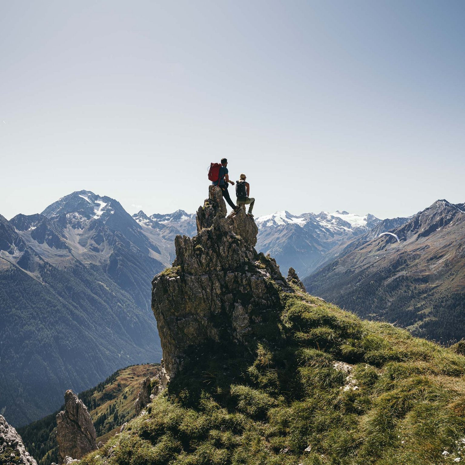 Stubaital: das Hotel mit Pool Zwei Wanderer auf einem Felsen mit Blick auf schneebedeckte Berge